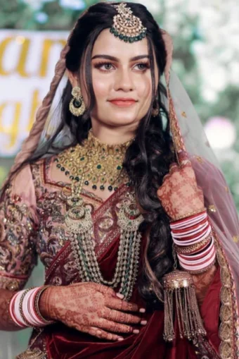 "A bride in a stunning maroon bridal dress with a glamorous bridal makeup look."